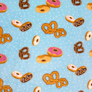 hooded blanket mostly pale blue with pictures of donuts and pretzels all over close up image of design