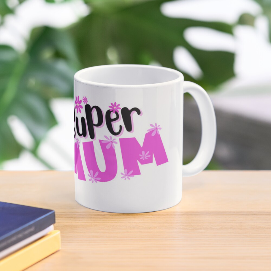 White coffee mug with a super mum design showing "super mum" in bold pink and black and a mum with several arms holding multiple items signifying mum can do all the things