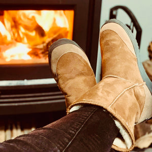 Mid calf height chestnut brown ugg boots worn in front of fire