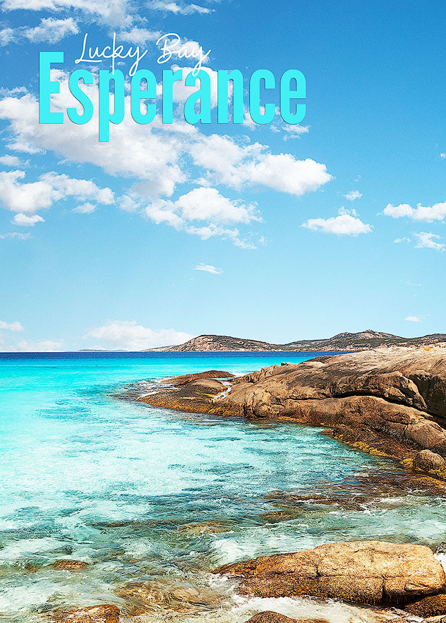 A photo of the image that is the 500 piece jigsaw puzzle,  it is a rocky outlook leading in to the beach with a blue sky and some clouds on a sunny day.  