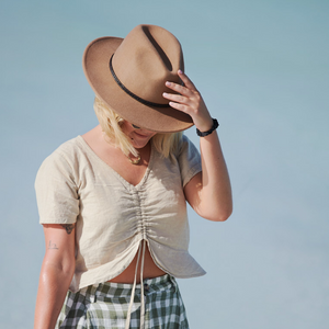 Fedora wool hat in caramel colour worn by a model at the beach