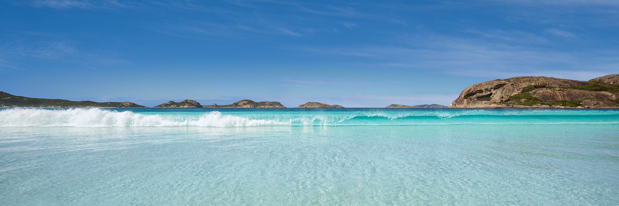 Lucky Bay aqua curling wave with large rock panorama in Esperance