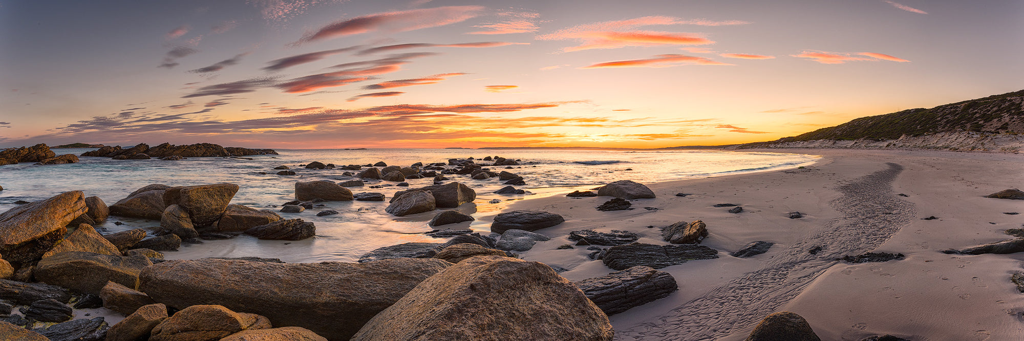 Observation Beach in Esperance at sunset with rocks in the sand and golden sky