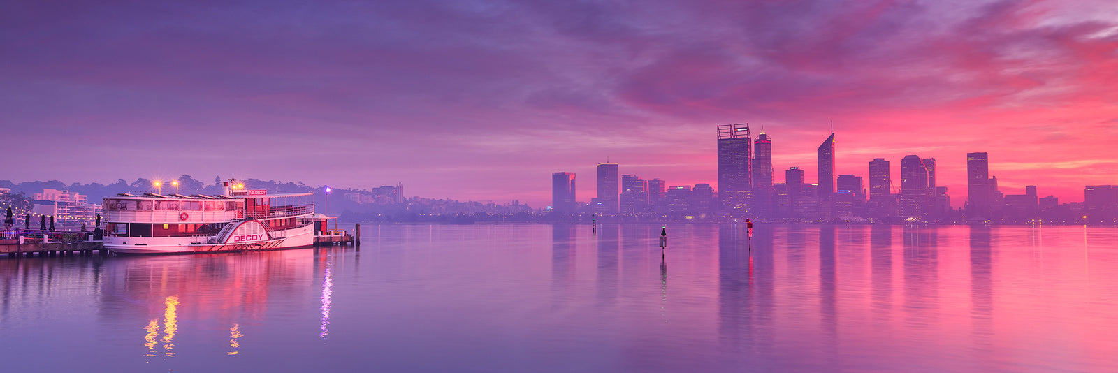 Perth City skyline from South Perth Foreshore smokey sky reflecting on water with paddle steamer to left of image