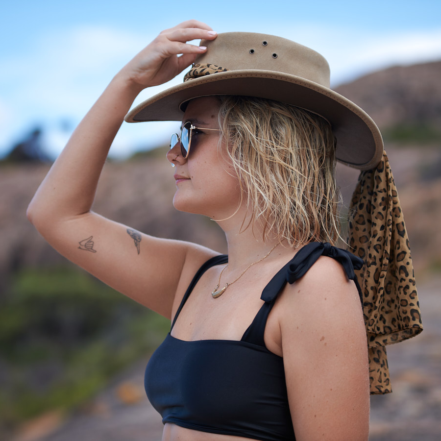 A model wearing the Jillaroo cowhide suede hat by Jacaru Australia in sand colour with a leopard look design brown scarf on the crown of the hat that hangs over the back of the hat